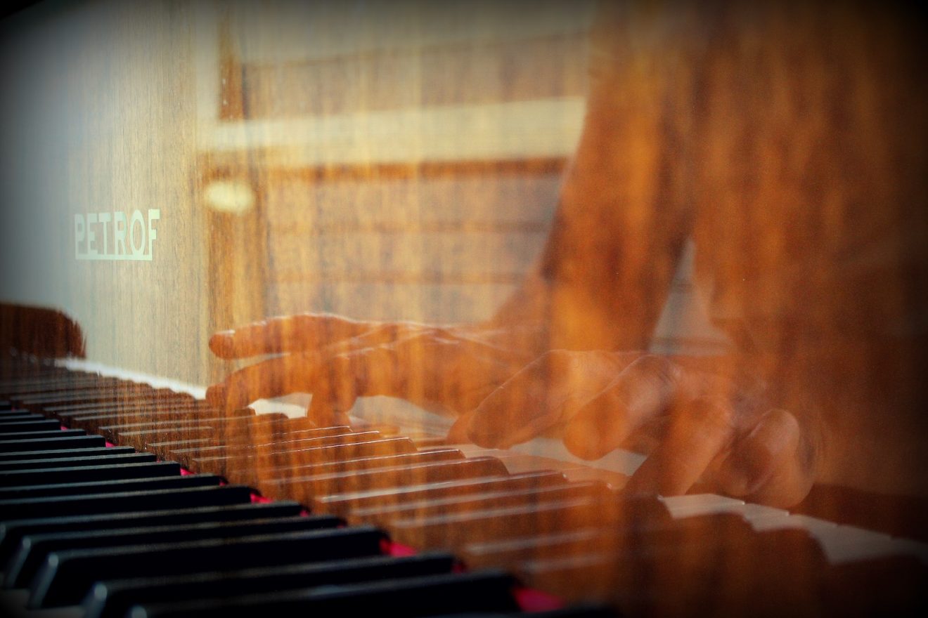person playing piano in front of white window curtain