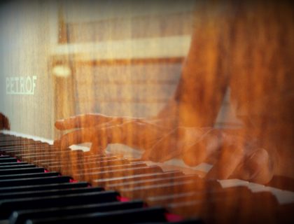person playing piano in front of white window curtain